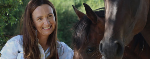 Woman smiling with a horse in a natural setting