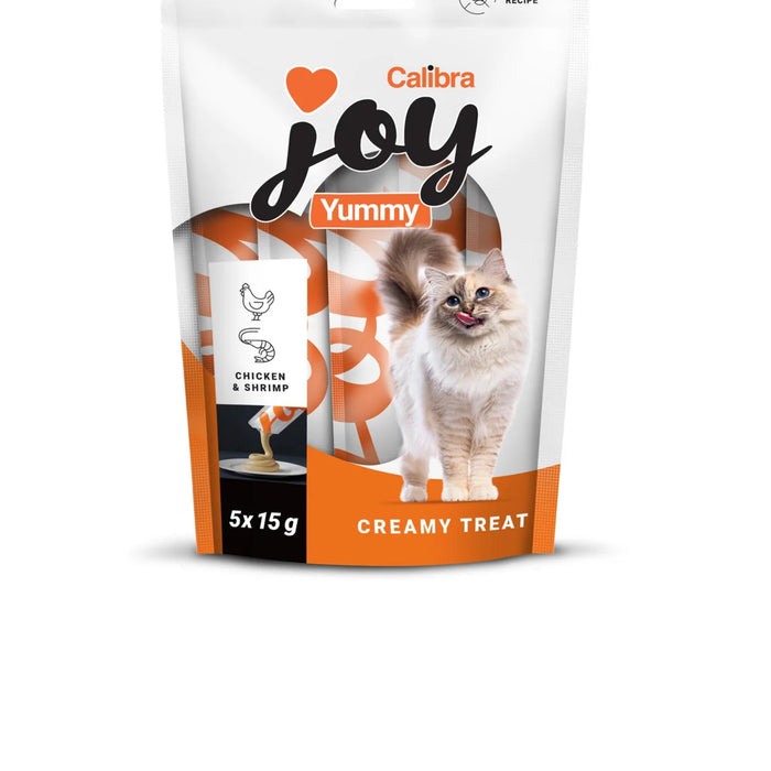 A stand-up pouch of Calibra Joy Yummy Creamy Treat cat food, featuring a fluffy cream-colored cat on the front, with orange and white packaging and text indicating 'Chicken & Shrimp' and '5x15g'.